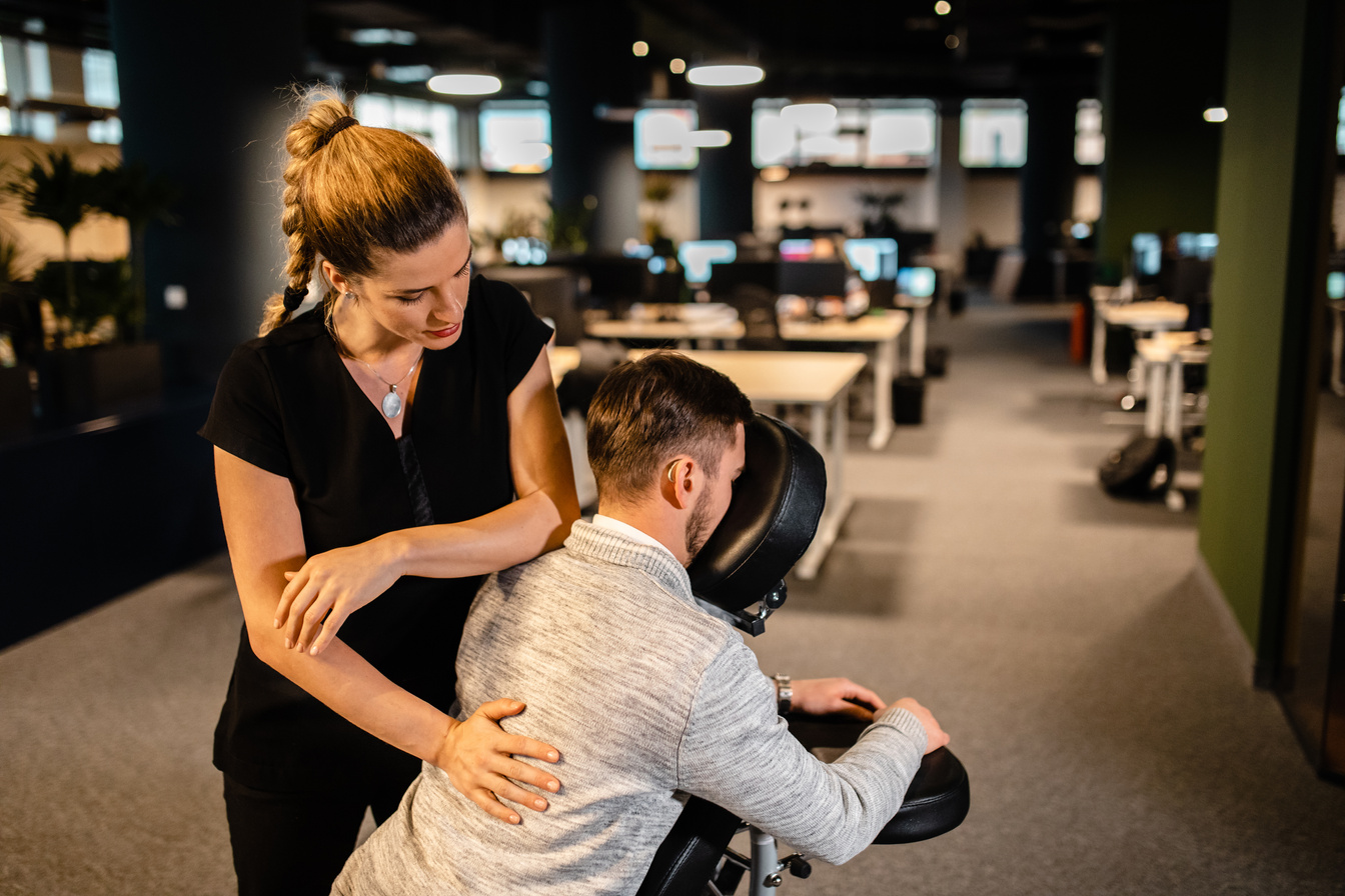 Exhausted web designer feeling a relief during back massage at corporate office